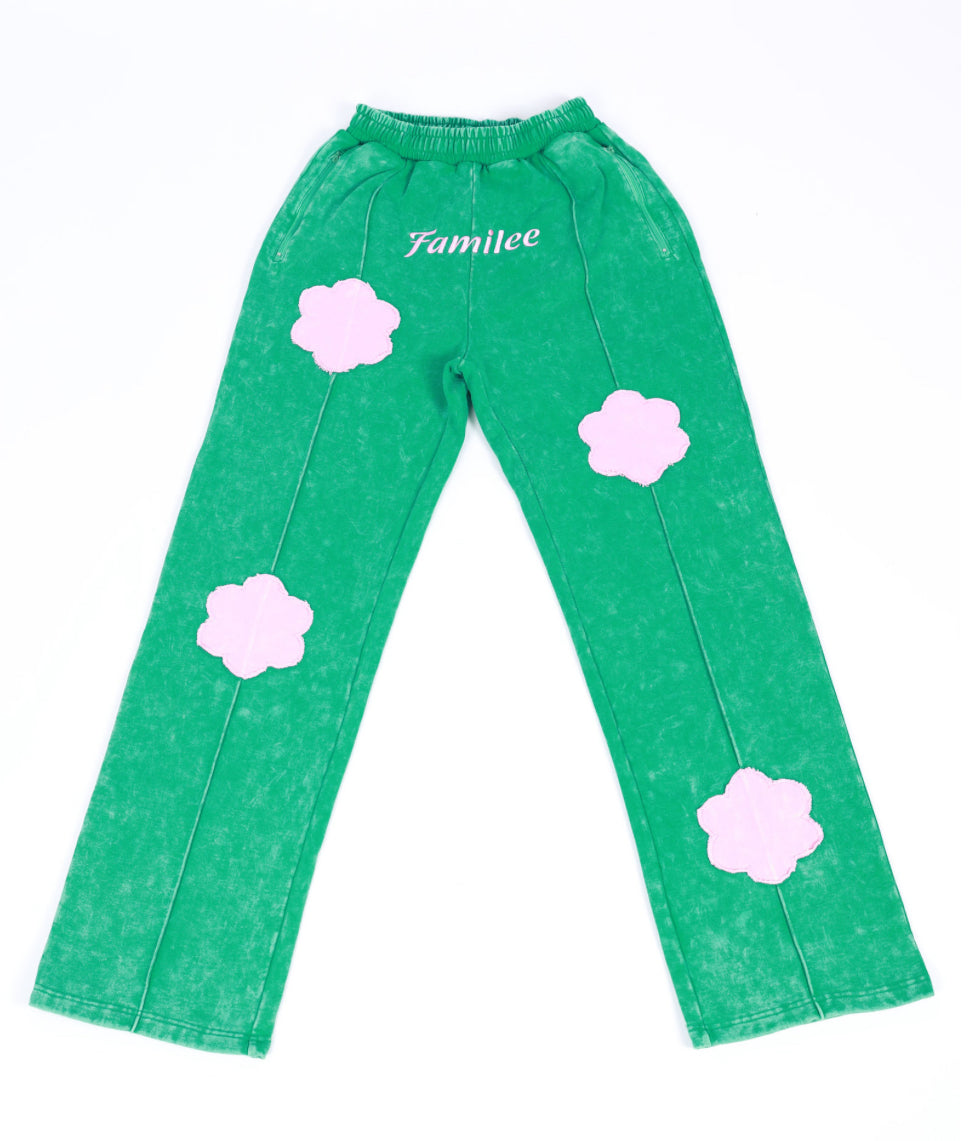 A pair of green sweatpants with pink cloud patterns and the brand ' Familee' written on Center.